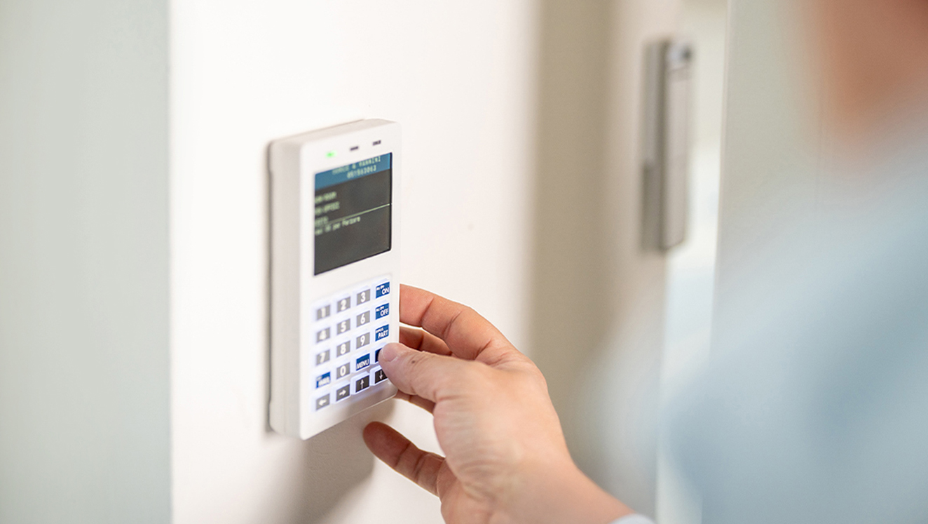 Una mano digita il codice di sicurezza su un keypad di un sistema antifurto, disattivandolo.