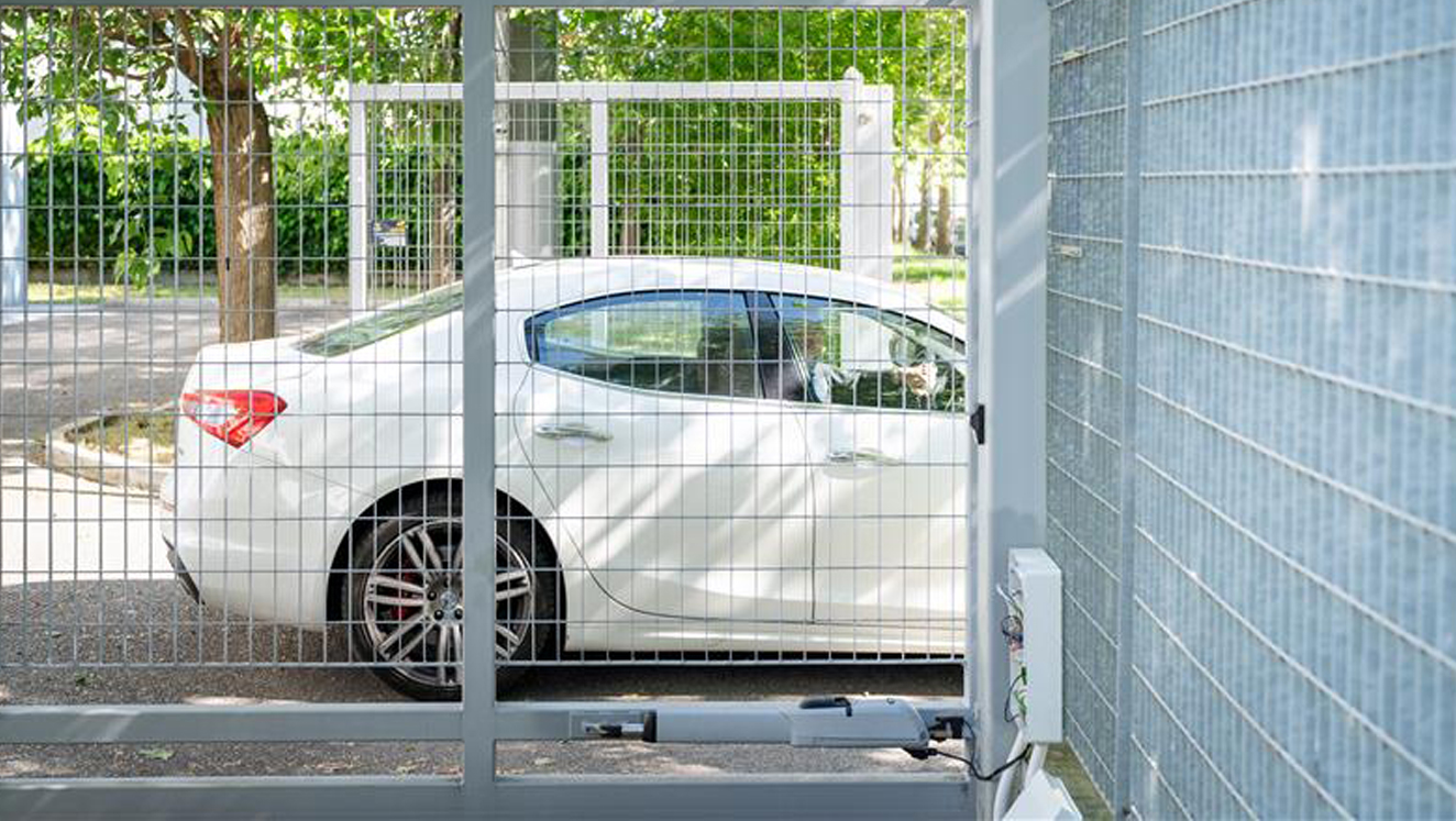 Una macchina di lusso è parcheggiata davanti a un cancello automatico chiuso. Nell'immagine vediamo anche l'automazione che movimenta il cancello automatico e le tecnologie installate su di esso.